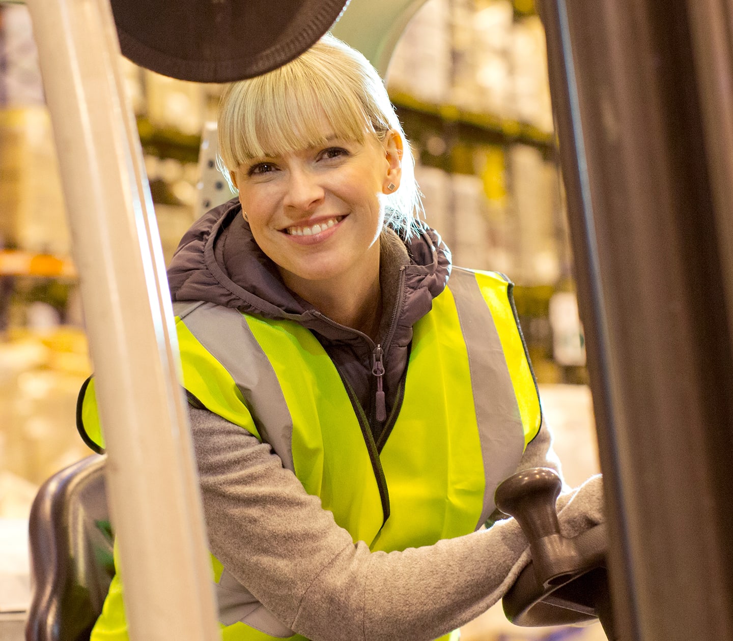 Smiling warehouse operator driving a forklift