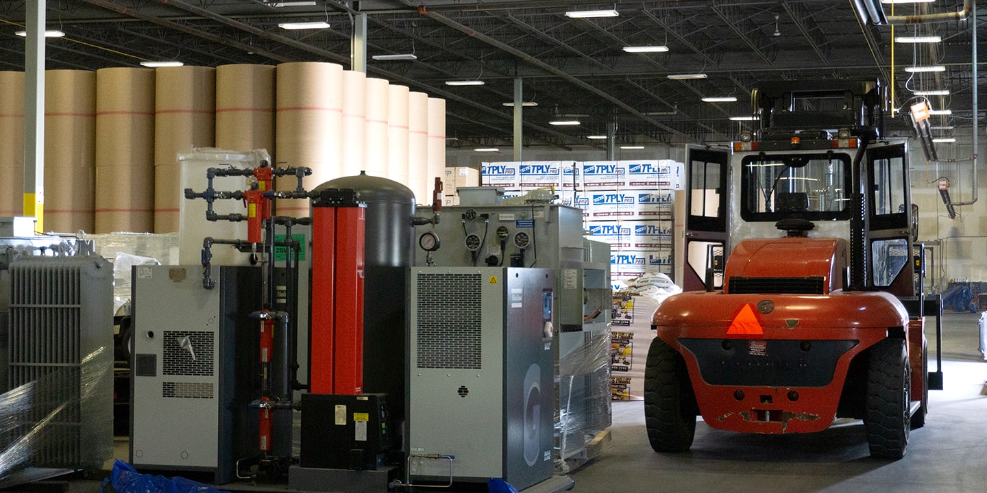 Heavy lift forklift parked beside industrial equipment bulk stored in an Active Warehousing warehouse